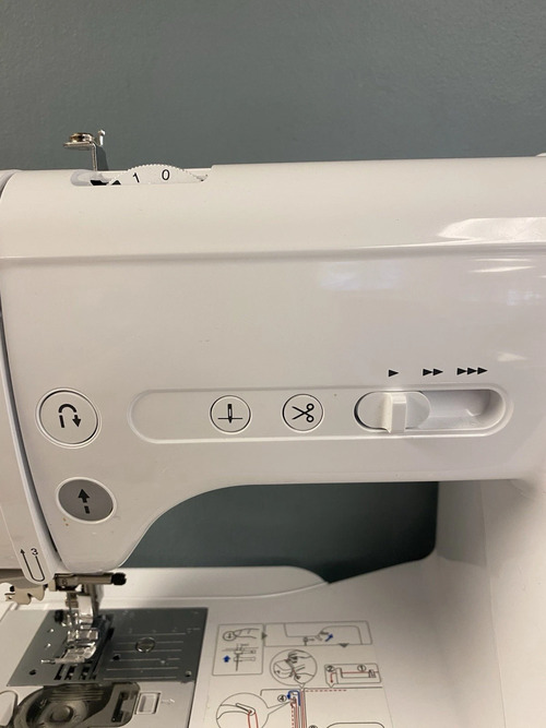 close-up—start/stop, needle-up/down, automatic thread-cutter buttons and speed slider controls.