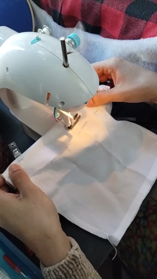Customer guiding light fabric through a CraftBud mini sewing machine