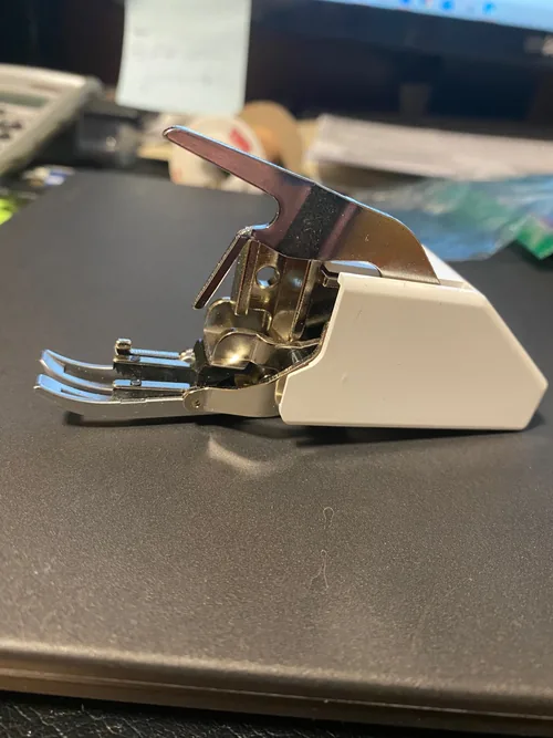 Walking foot photographed by a TL-18QVP owner who reported a bent guide after fabric bunching; the photo does not establish the cause.