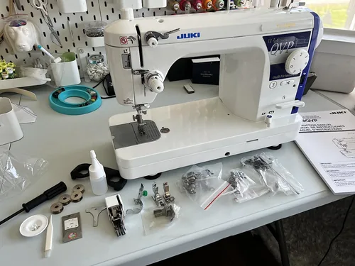 A customer’s Juki TL-18QVP with its manual, feet and other accessories laid out on the worktable.