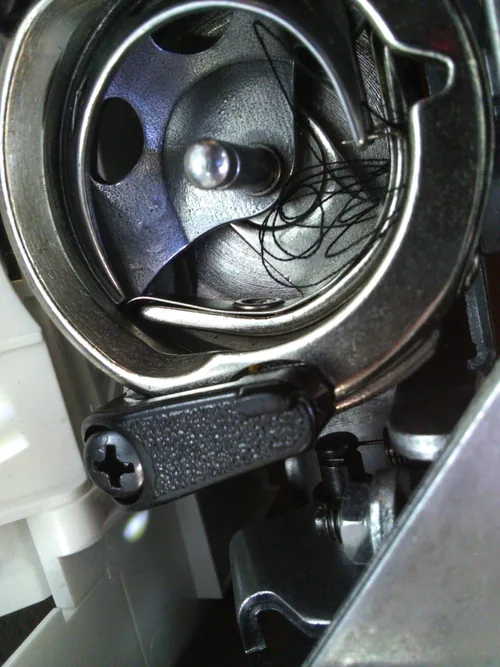 Thread tangled in the M2100 bobbin area, photographed by a customer reporting that the machine kept getting stuck. The photo alone does not establish the cause.
